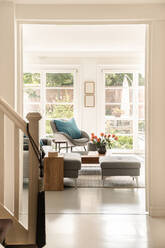 Innenansicht des Flurs mit Treppe und Türen, die zum geräumigen Wohnzimmer mit bequemem Sofa und Sessel in einer modernen Villa führen - ADSF33303