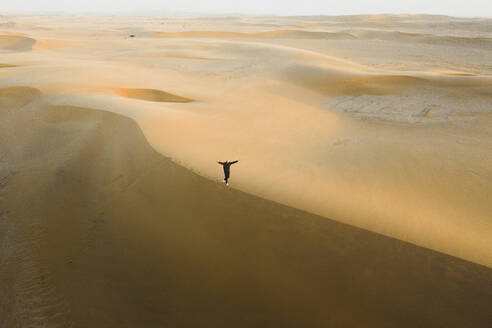 Luftaufnahme eines Spaziergängers auf einer Düne bei Sonnenaufgang in Swakopmund, Namibia. - AAEF13625