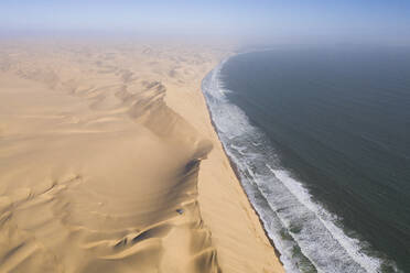 Luftaufnahme von zwei Geländewagen, die auf den Sanddünen entlang der Küstenlinie in der Nähe von Walvis Bay, Namibia, geparkt sind. - AAEF13636