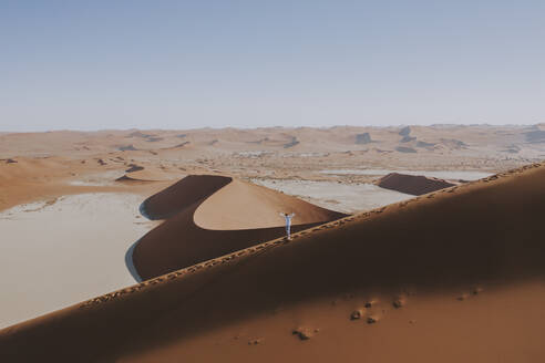 Luftaufnahme einer Person, die auf dem Dünenrand bei Dune 45 und Deadvlei, Sossusvlei, Namibia, spazieren geht. - AAEF13648