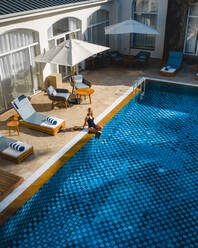Luftaufnahme einer schönen Frau, die sich in einem Luxushotel mit Swimmingpool entspannt, Pointe de Flacq, Mauritius. - AAEF13801