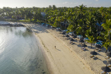 Luftaufnahme einer Frau, die am Strand von Poste de Flacq, Mauritius, am Ufer entlang spaziert. - AAEF13805