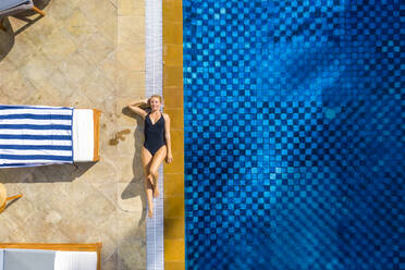 Luftaufnahme eines schönen Mädchens, das sich am Swimmingpool in einem Luxusresort in Pointe de Flacq, Mauritius, entspannt. - AAEF13815