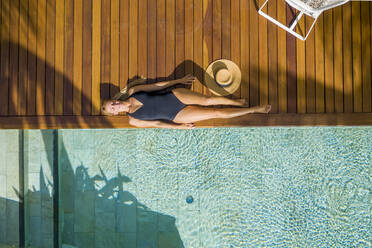 Luftaufnahme eines schönen Mädchens, das sich am Swimmingpool in einem Luxusresort in Pointe de Flacq, Mauritius, entspannt. - AAEF13817