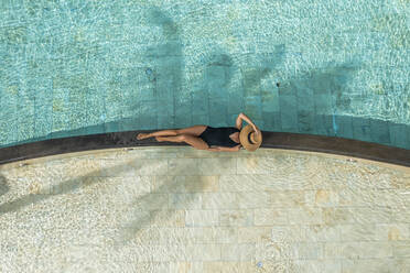 Luftaufnahme eines schönen Mädchens, das sich am Swimmingpool in einem Luxusresort in Pointe de Flacq, Mauritius, entspannt. - AAEF13819
