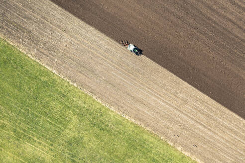 Luftaufnahme eines Traktors beim Pflügen eines Feldes an einem sonnigen Tag - WFF00551