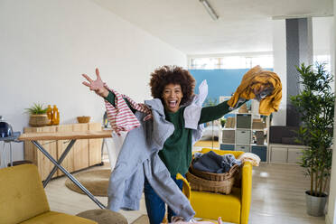 Playful young Afro woman with clothes on her having fun at home - GIOF14673