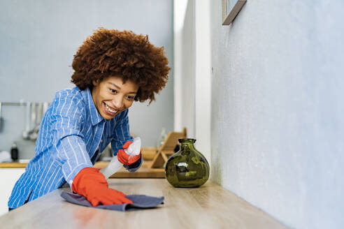 Lächelnde Afro-Frau beim Reinigen der Theke in der Küche - GIOF14726