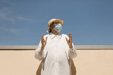 Senior woman wearing protective face mask on sunny day - GMLF01205