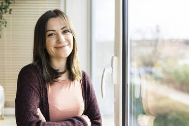 Young woman smiling near window at home - XLGF02521