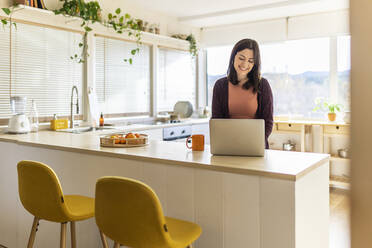 Businesswoman using laptop in kitchen working at home - XLGF02549
