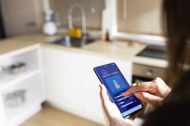 Frau verwendet Smart-Home-Anwendung auf dem Telefon zu Hause - XLGF02570