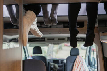 Freunde tragen Socken, die Beine hängen im Wohnmobil - MRRF01852