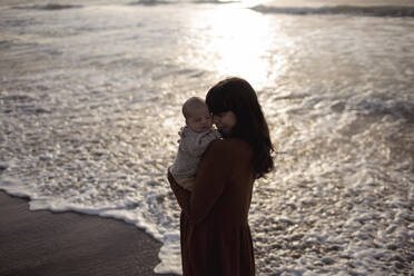 Loving mother embracing innocent baby boy at sunrise - GMLF01212