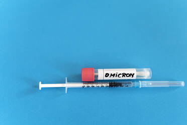 Abstrichröhrchen und Impfstoffspritze auf blauem Hintergrund - DRF01798
