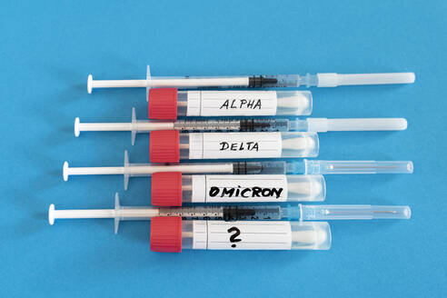 Abstrichröhrchen und Impfstoffspritzen auf blauem Hintergrund im Studio - DRF01799