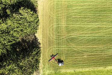 Luftaufnahme eines Traktors, der eine grüne Wiese im Vorfrühling bewegt - WFF00573