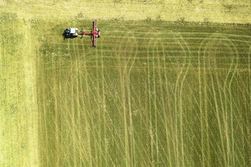 Luftaufnahme eines Traktors, der eine grüne Wiese im Vorfrühling bewegt - WFF00574