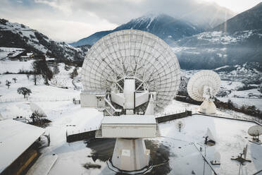 Luftaufnahme einer grossen Satellitenschüssel am Bahnhof Signalhorn im Winter, Leuk, Schweiz. - AAEF13883