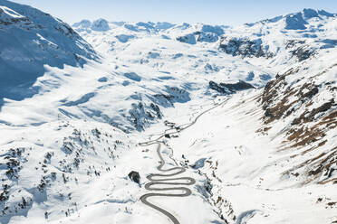 Luftaufnahme einer Zickzackstraße in den Bergen im Winter mit Schnee, Bivio, Schweiz. - AAEF13889