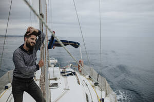 Nachdenklicher Mann lehnt am Mast eines Segelboots im Mittelmeer - GMLF01237