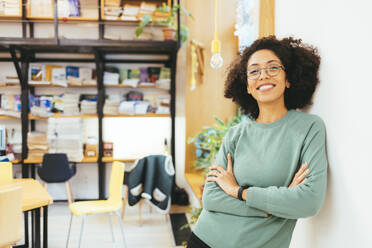 Businesswoman smiling and leaning on wall at office - OYF00665