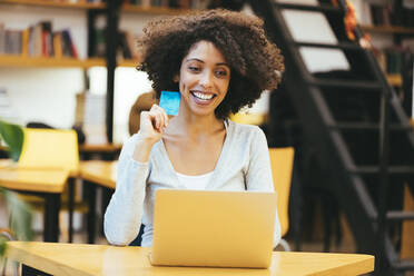 Lächelnde Geschäftsfrau mit Kreditkarte und Laptop im Büro - OYF00685
