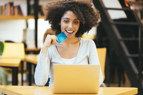 Lächelnde Geschäftsfrau beim Online-Einkauf per Kreditkarte mit Laptop im Büro - OYF00686