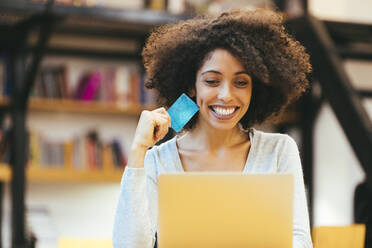 Fröhliche Geschäftsfrau mit Kreditkarte und Laptop im Büro - OYF00689