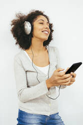 Frau hört Musik über Kopfhörer vor weißem Hintergrund - OYF00694