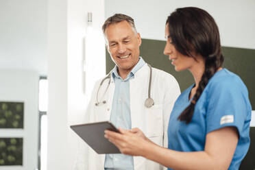 Krankenschwester bespricht sich mit lächelndem Arzt über Tablet-PC im Krankenhaus - JOSEF06517