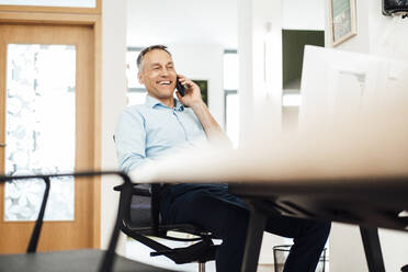 Happy businessman talking on smart phone in coworking office - JOSEF06534