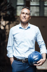 Confident architect with hardhat standing in office - JOSEF06562