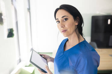 Nurse in blue medical scrubs holding tablet PC in hospital - JOSEF06578