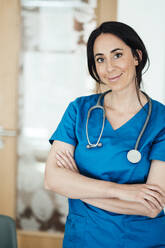 Smiling doctor with with arms crossed in hospital - JOSEF06580