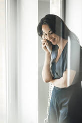 Smiling businesswoman talking on telephone in coworking office - JOSEF06597