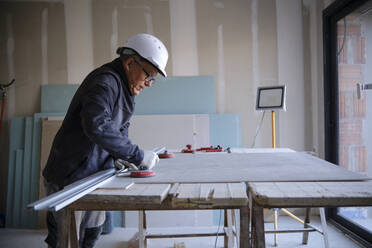 Bauarbeiter mit Rigipsplatten auf einer Werkbank auf der Baustelle - AGOF00216