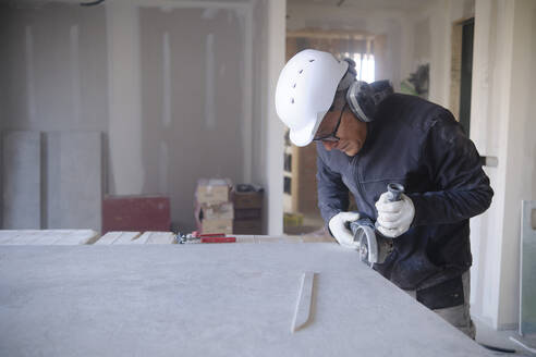 Construction worker cutting sheetrock with power tool at site - AGOF00217