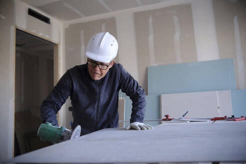 Concentrated worker with power tool at construction site - AGOF00218