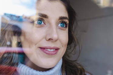 Nachdenkliche Frau mit blauen Augen durch Glas gesehen - AMWF00080