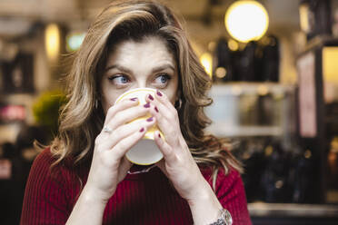 Junge Frau trinkt Kaffee in einem Cafe - AMWF00089