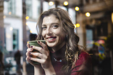 Lächelnde Frau mit Einweg-Kaffeebecher im Café - AMWF00091