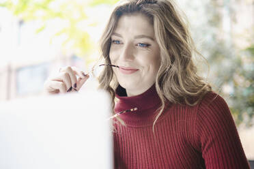 Smiling woman with laptop in cafe - AMWF00102