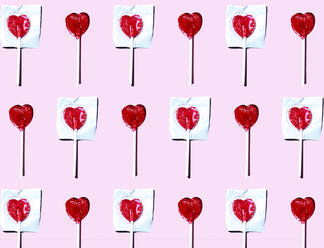 Pattern of heart shaped lollipops flat laid against pink background - EGHF00323