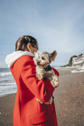 Junge Frau mit Yorkshire-Terrier am Strand - OMIF00436