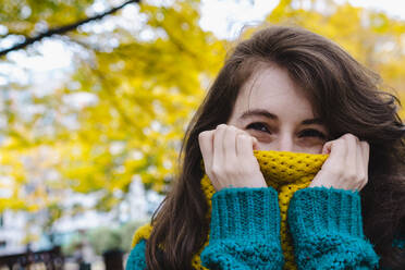 Woman covering mouth with scarf in park - AMWF00137