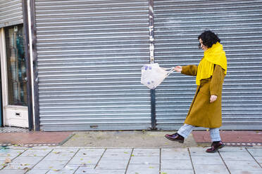 Junge Frau mit Plastikflaschen in einer Netztasche auf dem Gehweg - AMWF00148