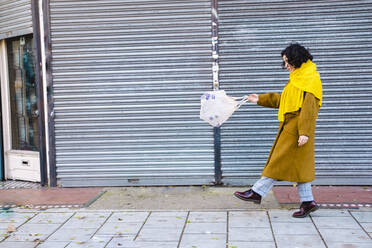 Young woman walking with plastic bottles in mesh bag on footpath - AMWF00148