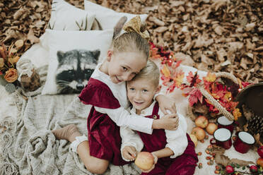 Lächelnde Schwester umarmt Bruder beim Picknick in Weihnachten - GMLF01252