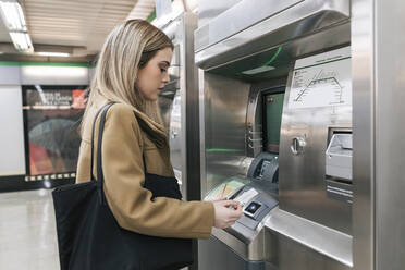 Frau mit Geldbörse, die am Bahnhof mit Kreditkarte bezahlt und eine Fahrkarte kauft - JRVF02661